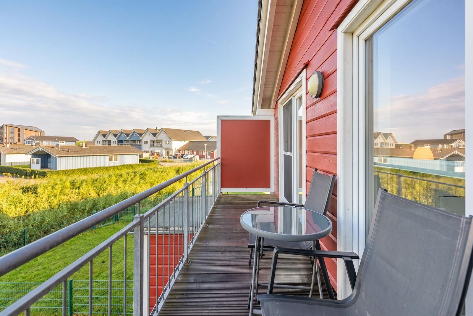 Terrace with table and chairs, view of houses and green areas.