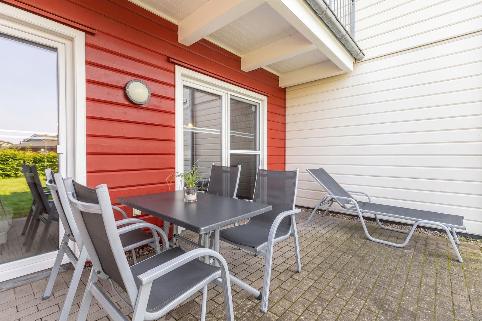 Terrace with table, chairs, and lounge. Red and white wooden structure.