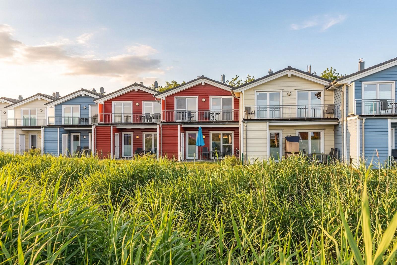 Row of colorful vacation homes with balconies and grass in the foreground.