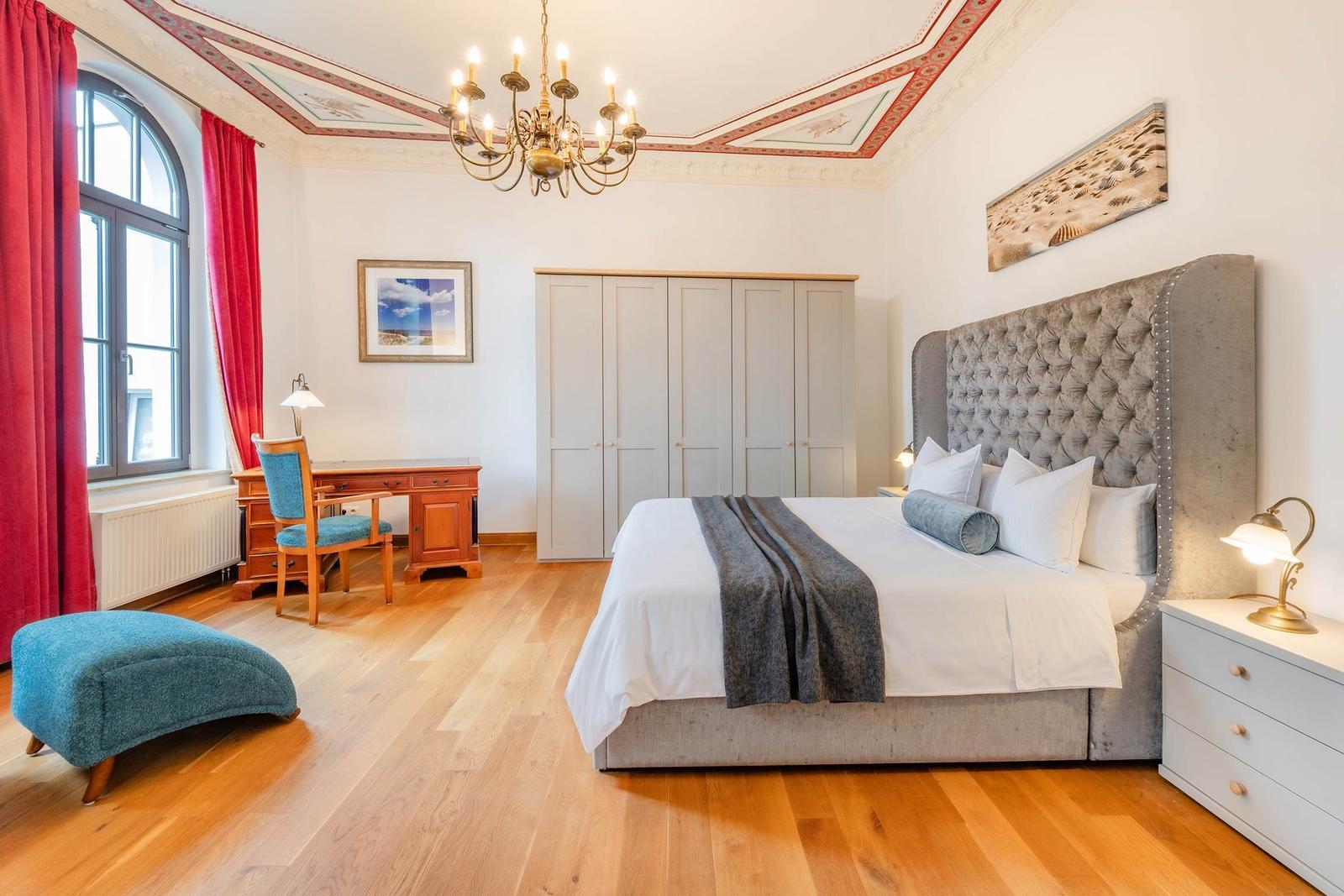 Schlafzimmer mit Bett, Schreibtisch, Kleiderschrank und Holzboden.