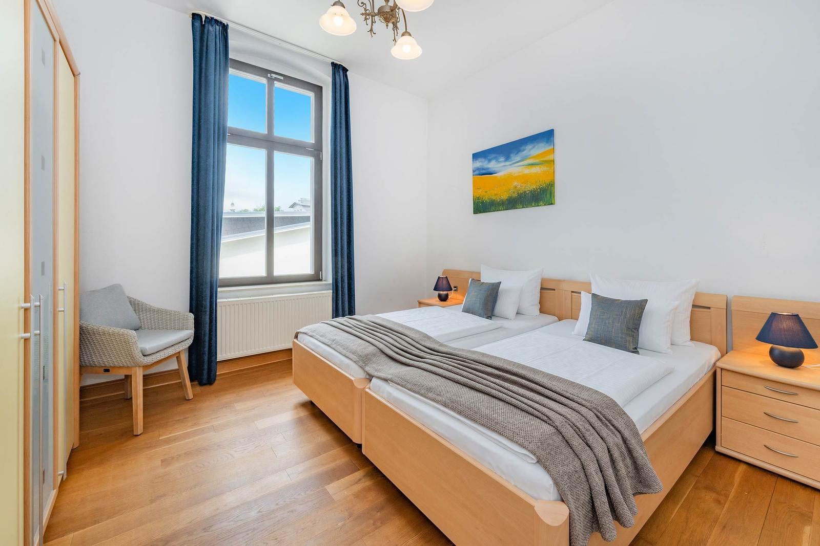 Ein Schlafzimmer mit Doppelbett, Holzmöbeln und großem Fenster mit Blick.