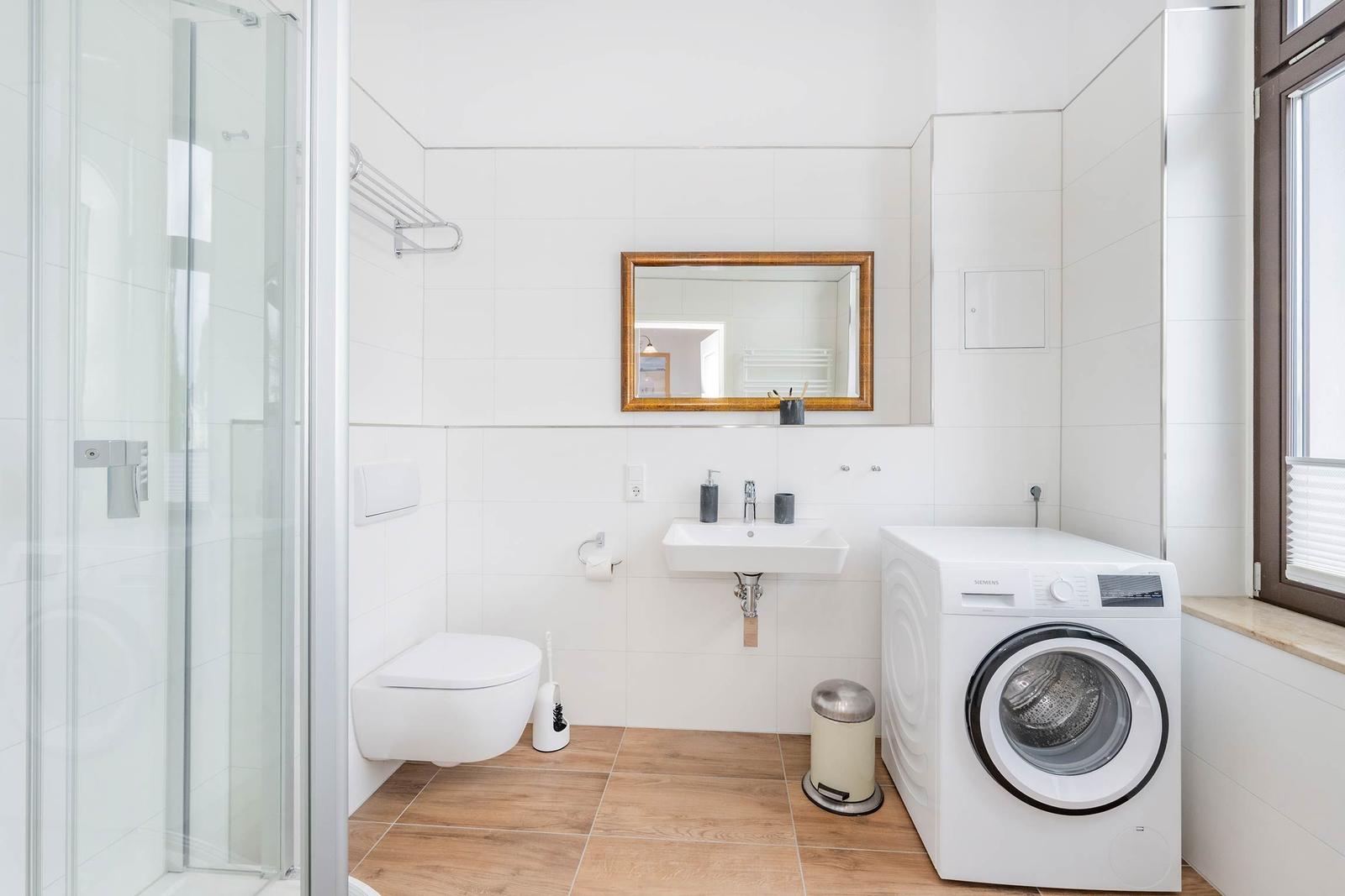 Badezimmer mit Dusche, Toilette, Waschbecken und Waschmaschine.