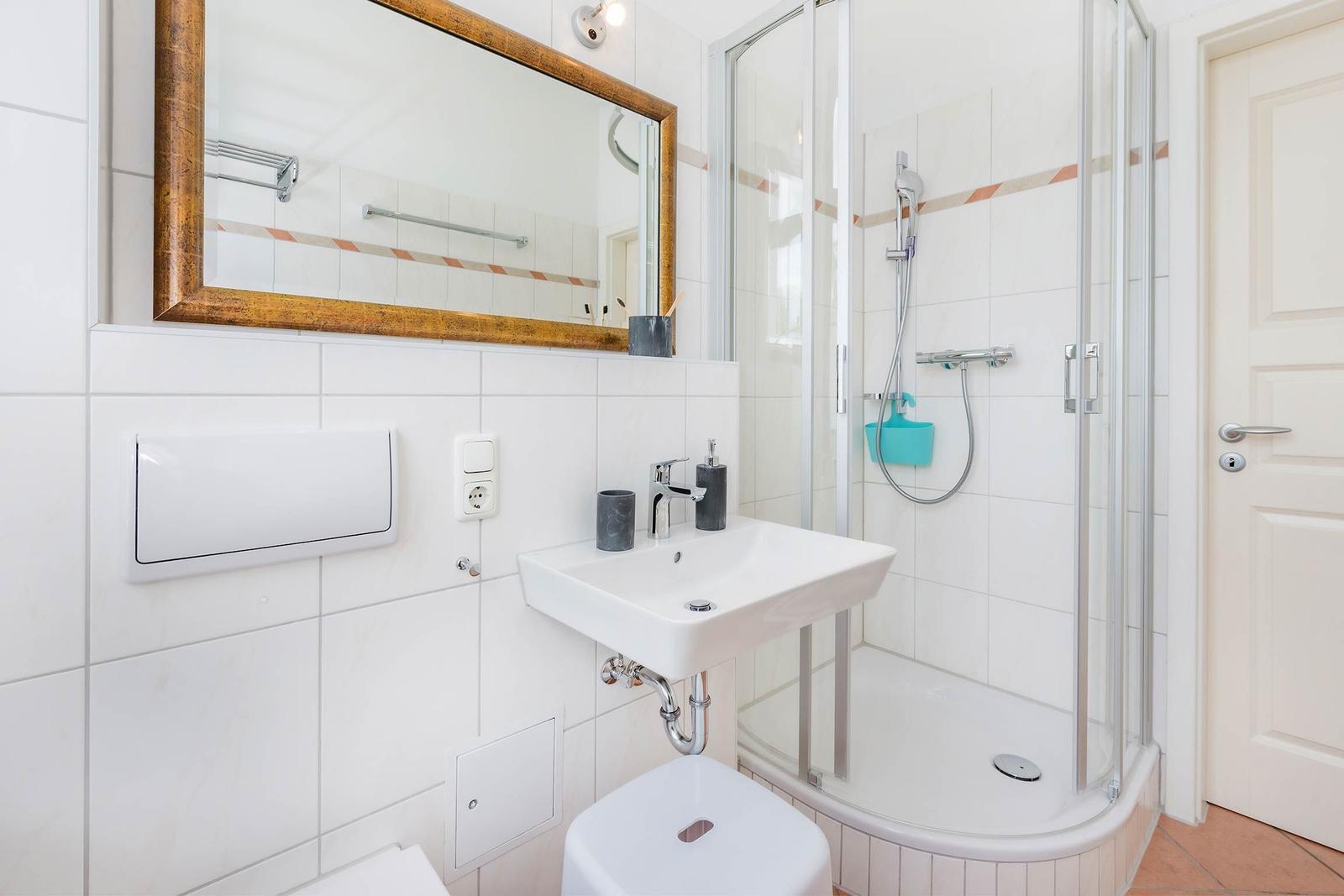 Badezimmer mit Dusche, Waschbecken und Spiegel