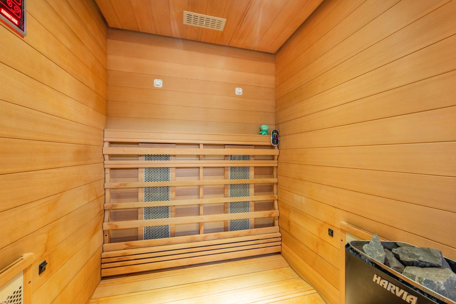Sauna mit Holzwand, Sitzbänken und Steinen. Harvia-Logo sichtbar.