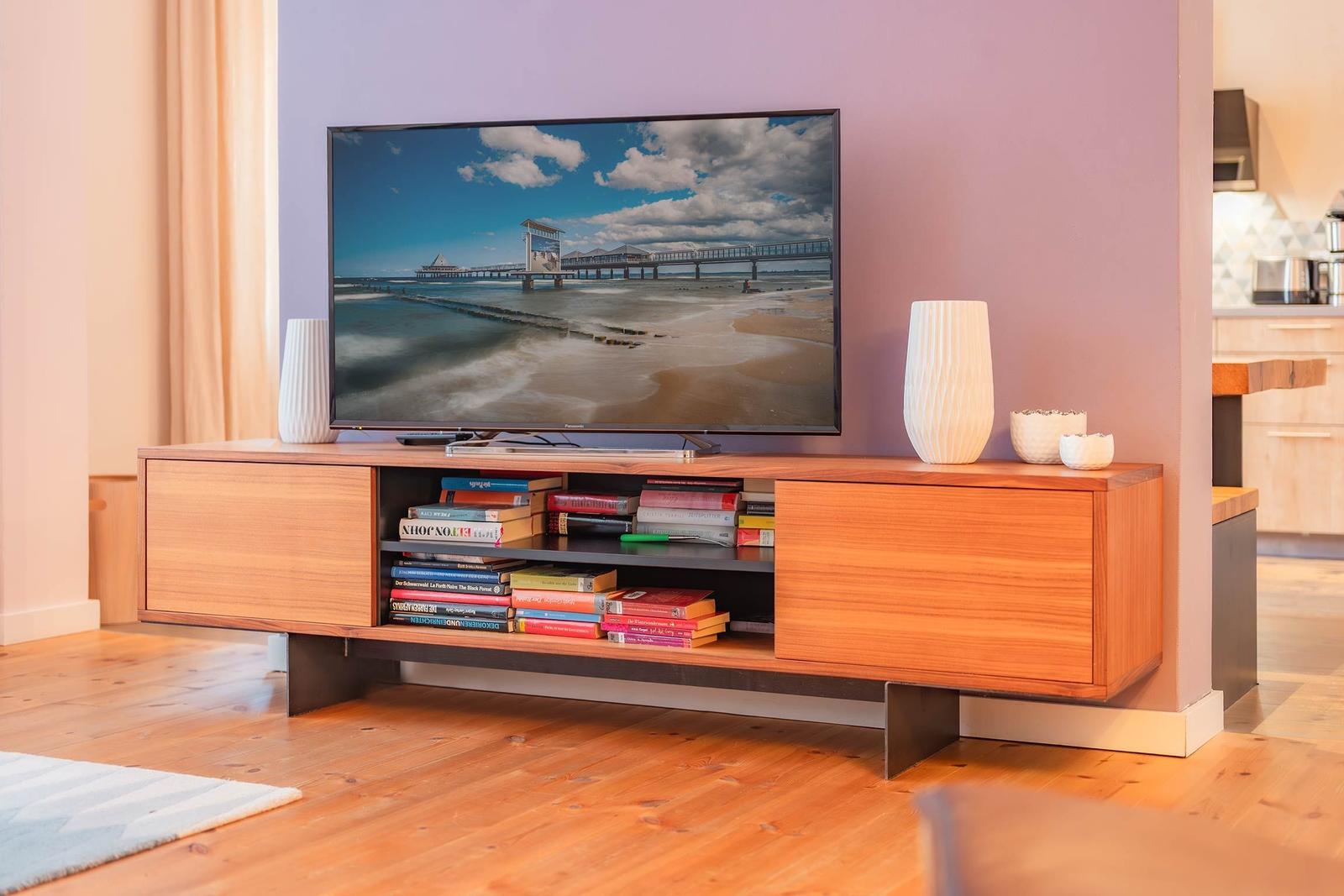 TV auf Holzregal mit Büchern und Vasen. Hintergrund Wand in Lila.