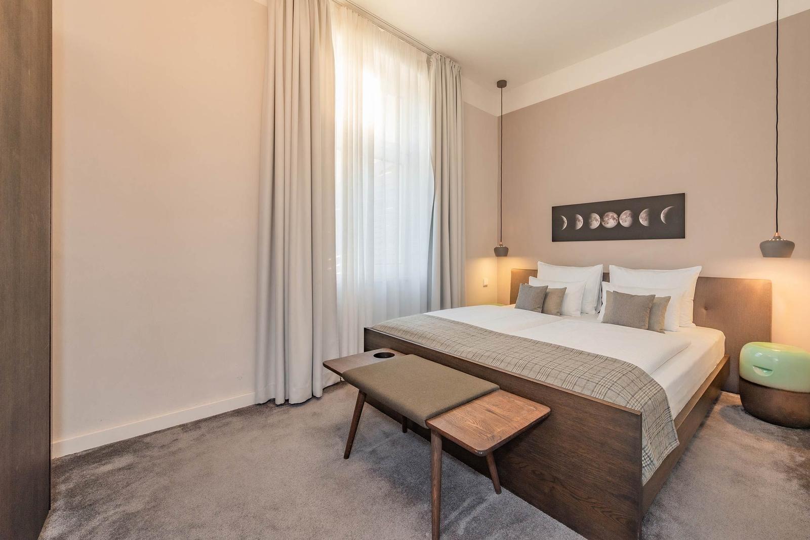 Schlafzimmer mit Doppelbett, Fenster, Vorhang und Wandbild.