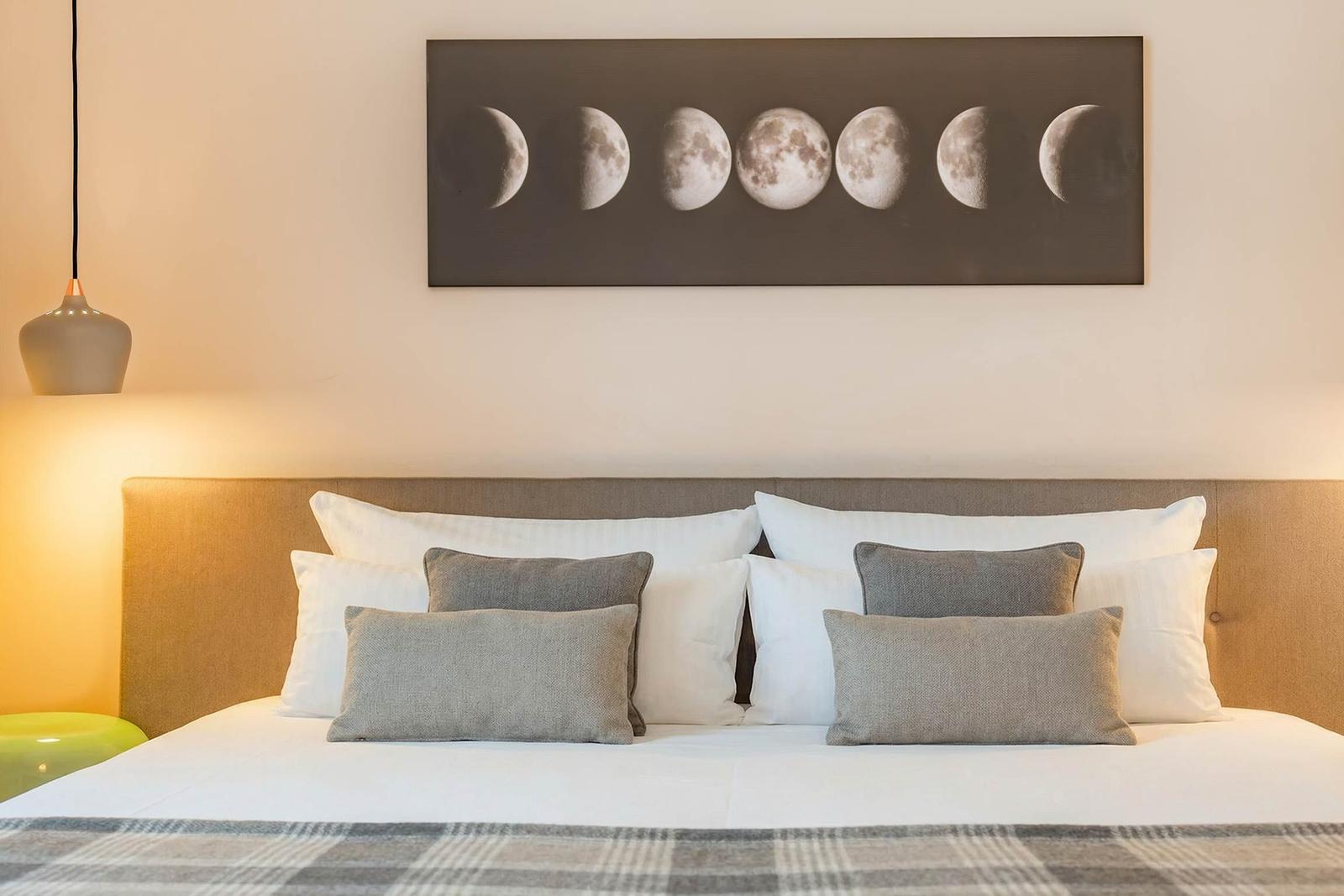 Ein Bett mit Kissen und einem Wandbild der Mondphasen.