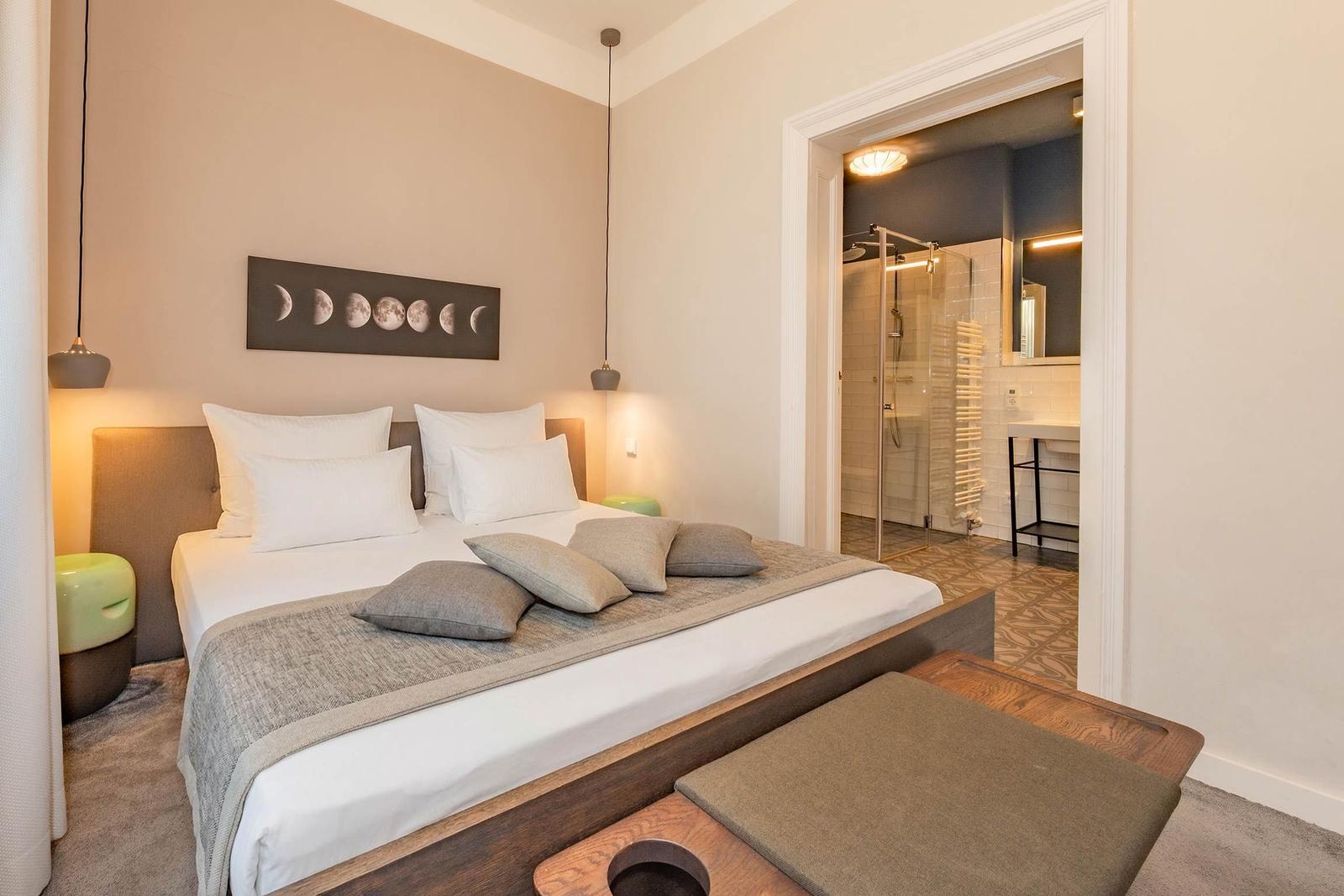 Schlafzimmer mit Doppelbett, Wandbild und angrenzender Dusche.