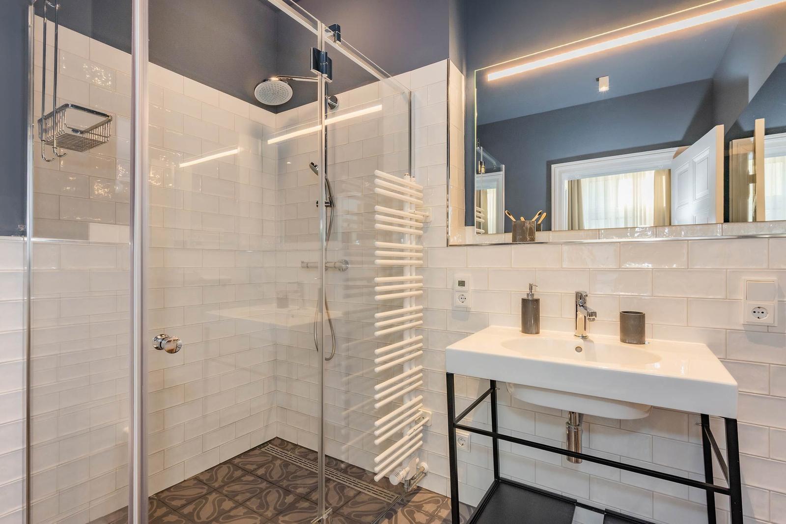 Badezimmer mit Dusche, Waschbecken und Spiegel
