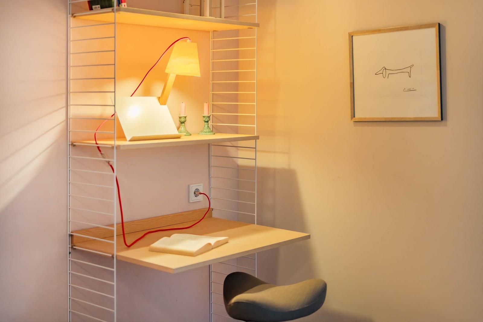 Wohnraum mit Schreibtisch, Stuhl und Lampe. Wandbild mit Zeichnung.