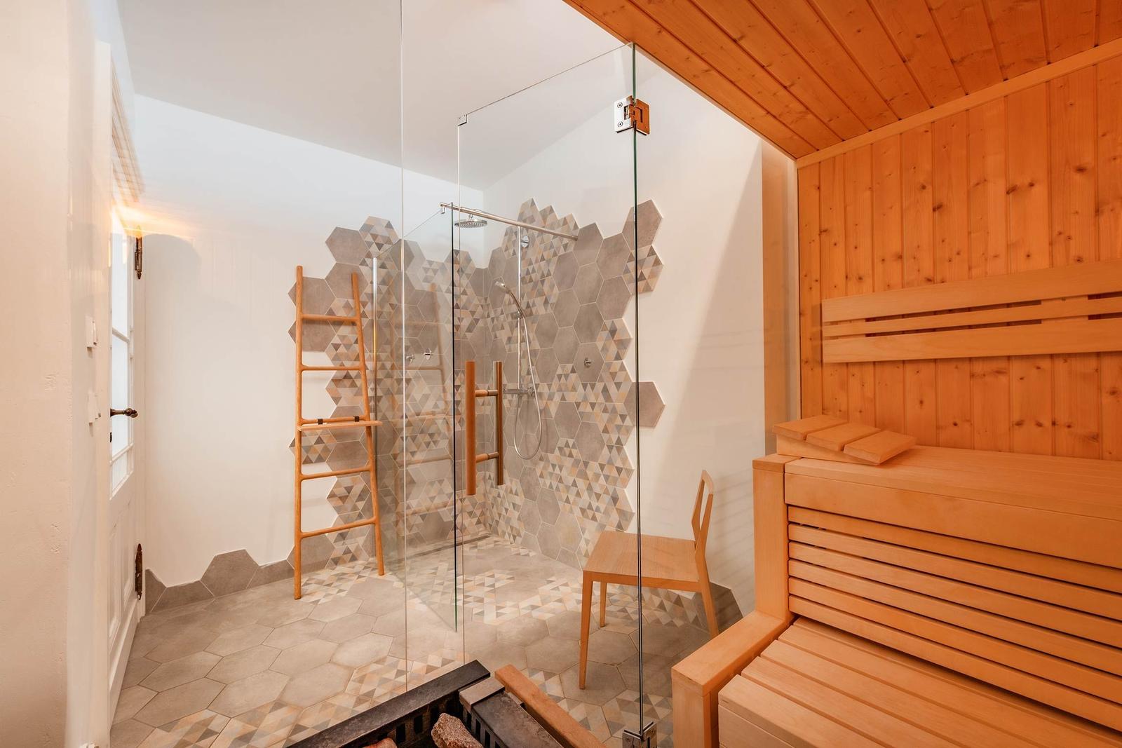 Dusche mit Glaswand und Holzregal. Sauna mit Holzbank und Wandverkleidung.