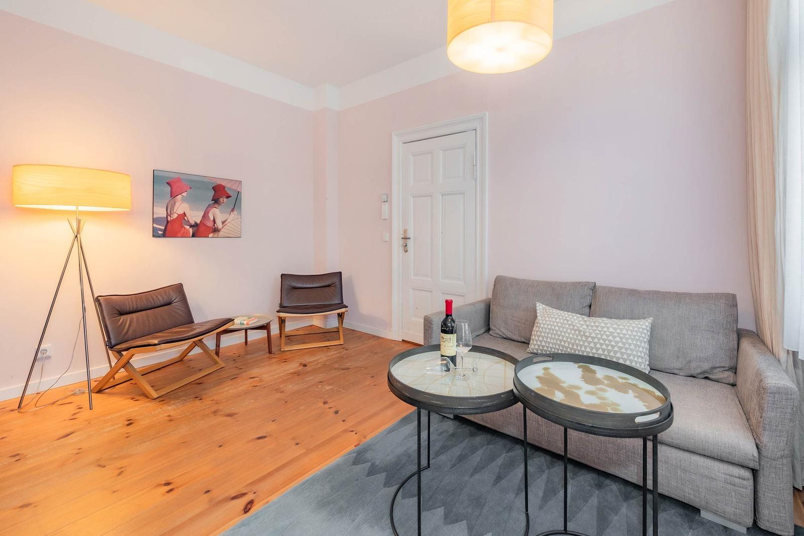 Wohnzimmer mit Sofa, zwei Tischen, zwei Stühlen und einer Wandlampe.