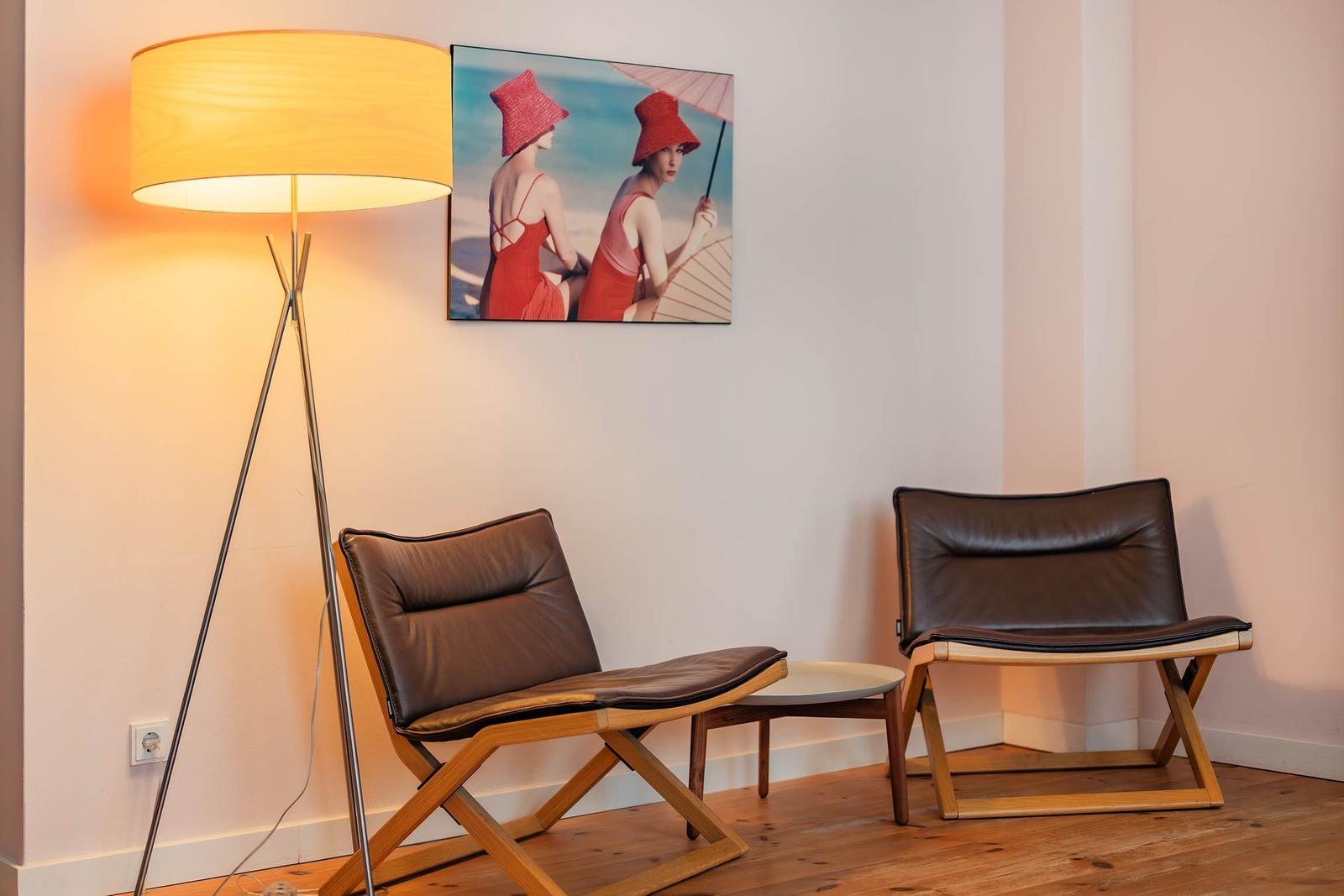 Zwei braune Ledersessel und eine Stehlampe neben einer Wand mit Bild.