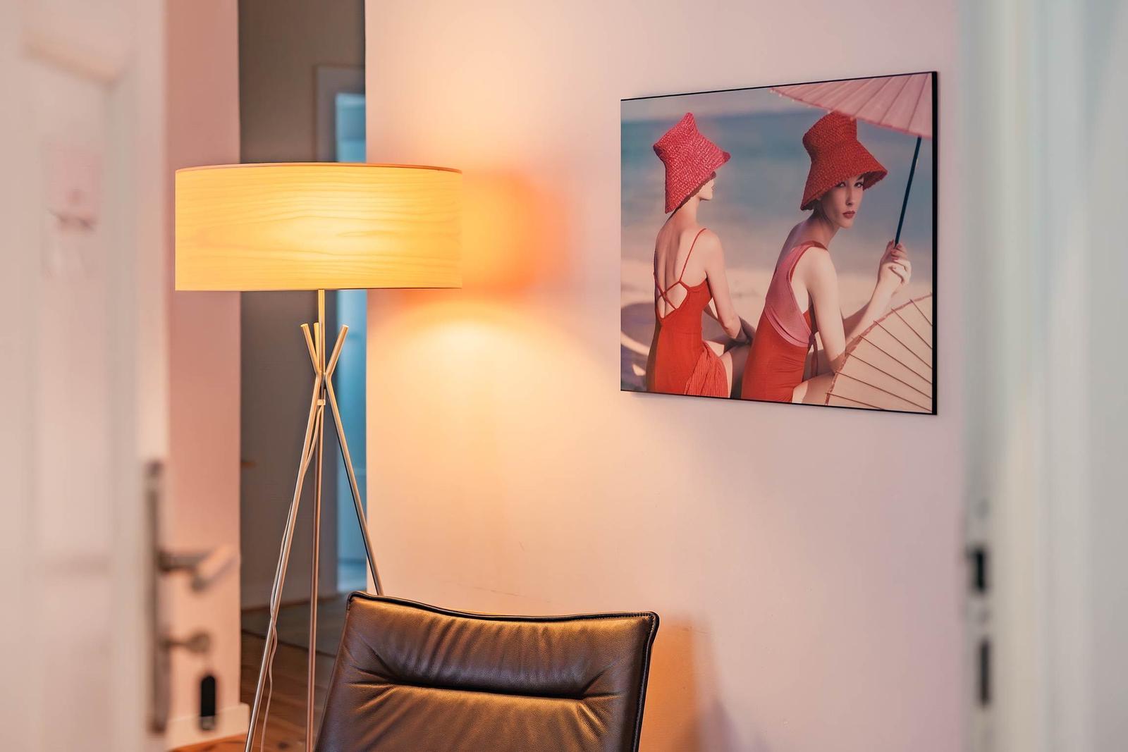 Helle Wand mit Wandbild und Stehlampe neben einem Sessel.