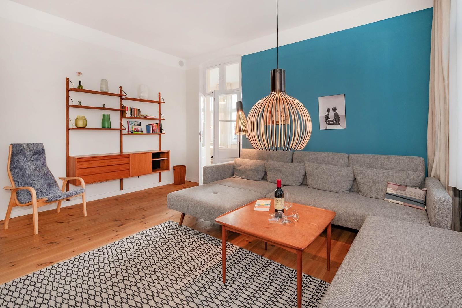 Wohnzimmer mit grauem Sofa, Holztisch und blauer Wand.