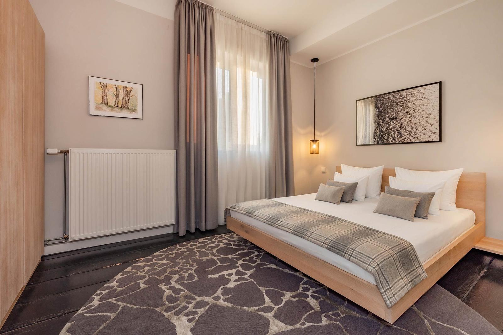 Schlafzimmer mit Bett, Vorhängen und Wandbildern