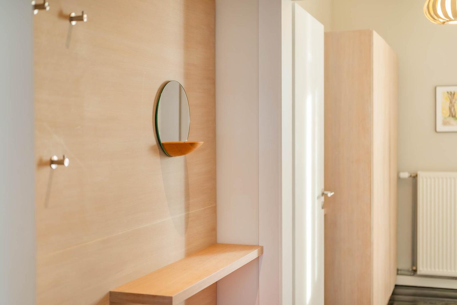 Duschbereich mit Holzwand, runden Spiegel und Holzbank