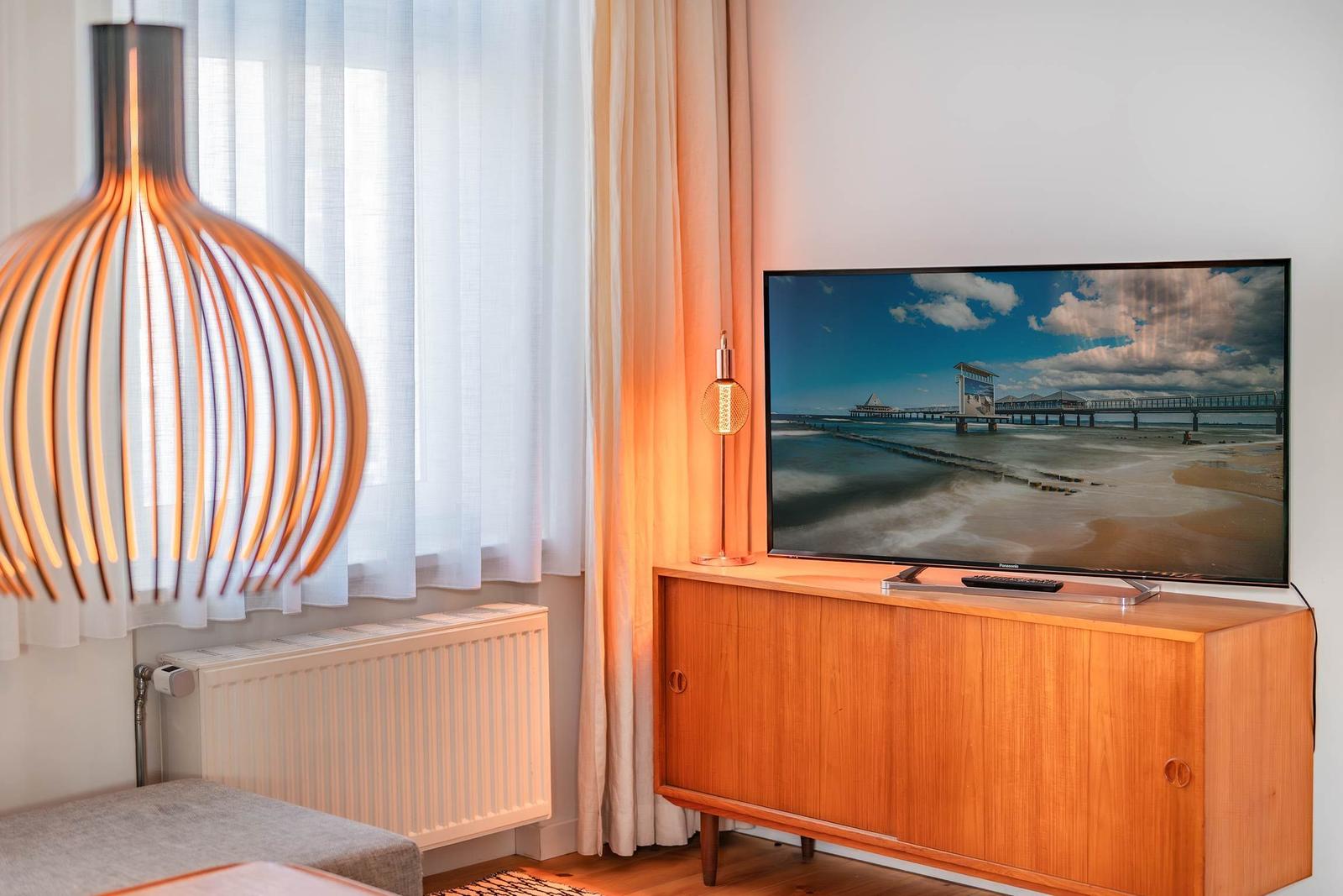 TV auf Holzboard, Lampe und Fenster mit Vorhängen
