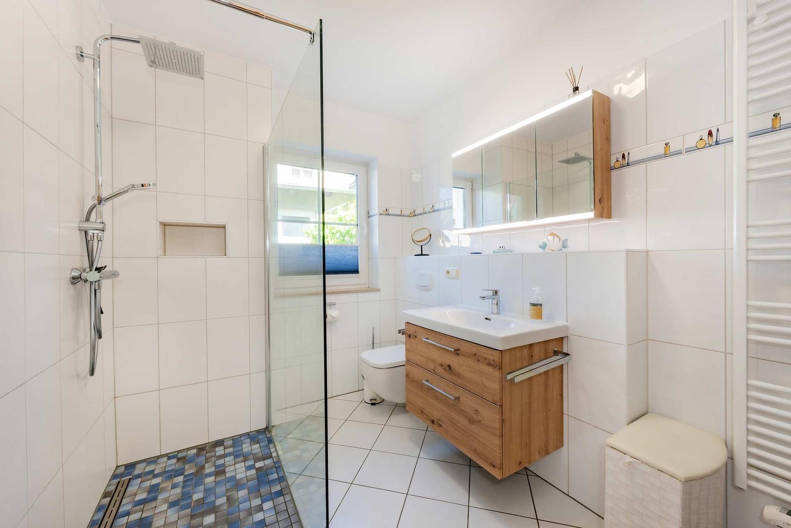 Bad mit Dusche, Waschbecken und Toilette. Holzwaschtisch und Spiegelschrank.