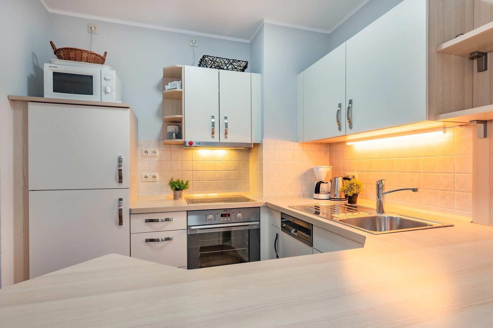 Küche mit Kühlschrank, Herd, Spüle und Schränken.