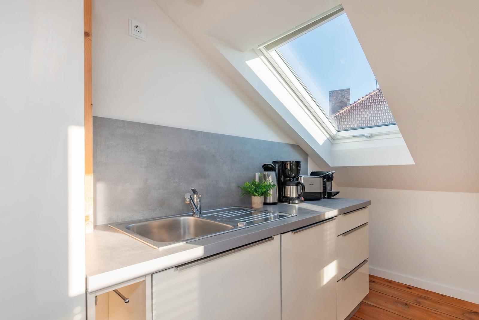 Küche mit Dachfenster, Spüle und Küchengeräten.