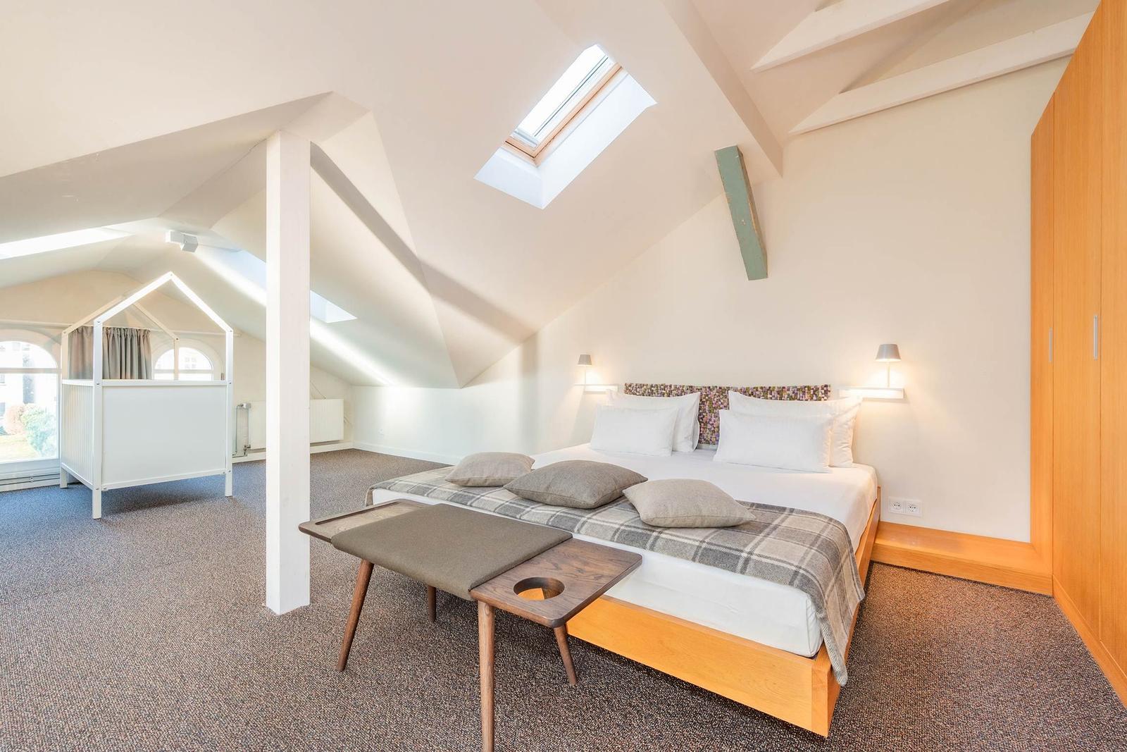 Schlafzimmer mit Dachschrägen, Bett, Kleiderschrank und Kinderhütte.