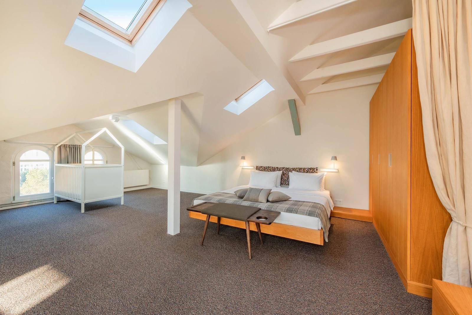 Schlafzimmer mit Dachschrägen, Dachfenstern, Bett, Kleiderschrank und Kinderbett.