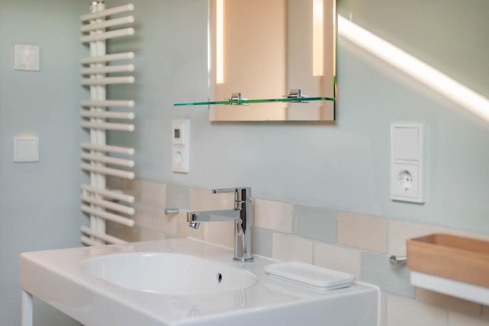 Badezimmer mit Waschbecken, Spiegel und Heizkörper