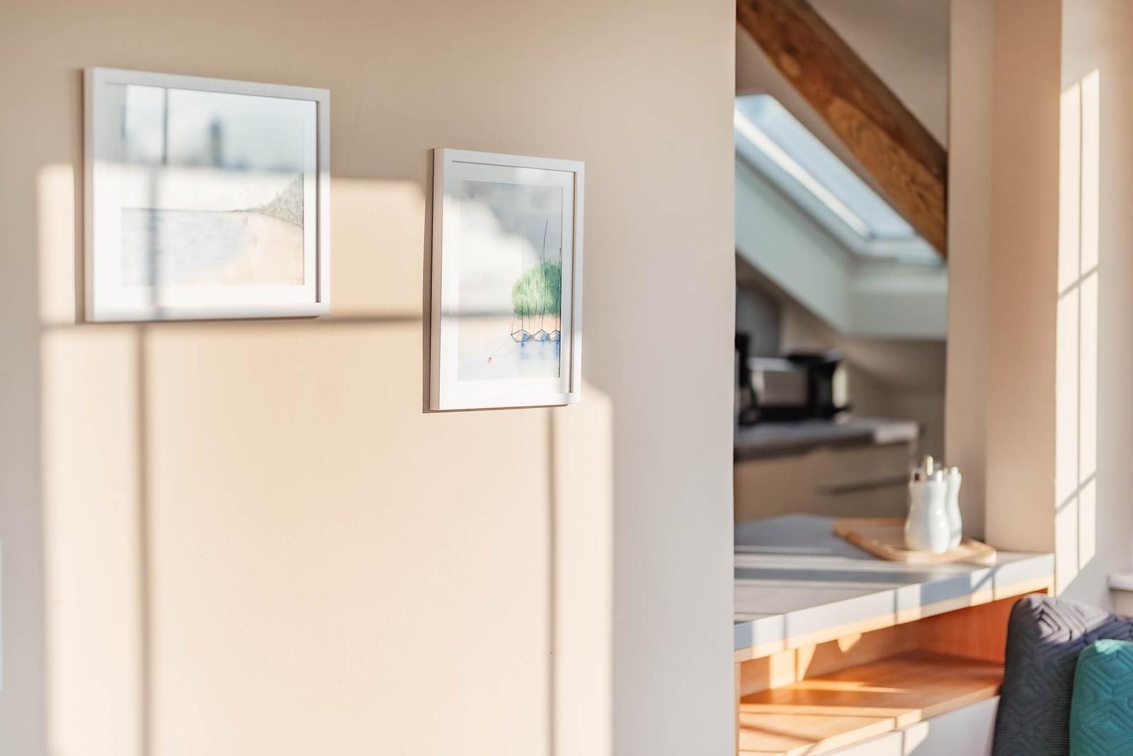 Zwei Bilder an der Wand, Blick in die Küche mit Dachfenster und Küchenarbeitsplatte.