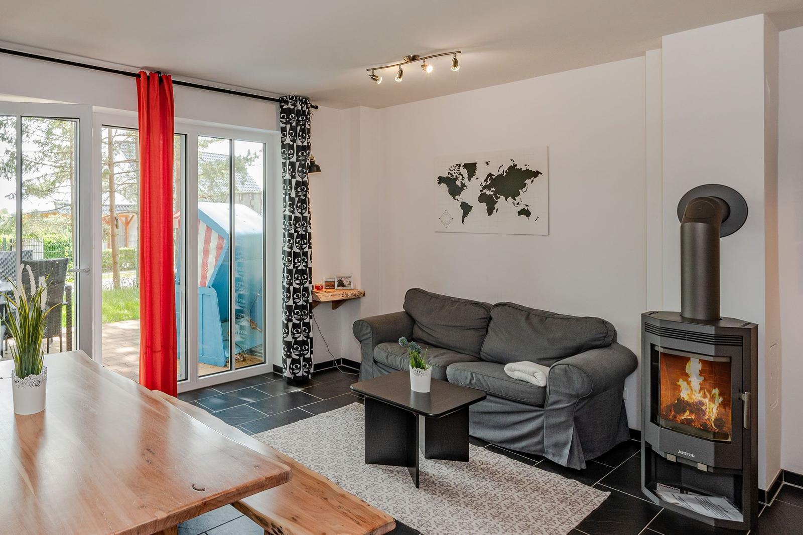 Wohnzimmer mit Sofa, Kamin und Glasfront zum Garten
