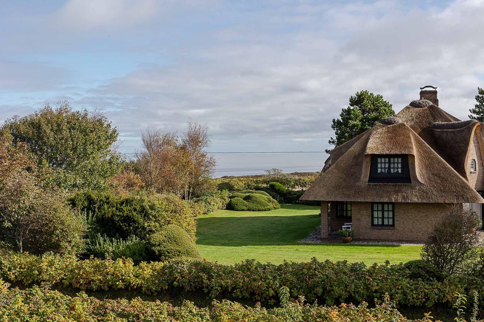 Haus mit Strohdach und Gartenblick auf Wasser