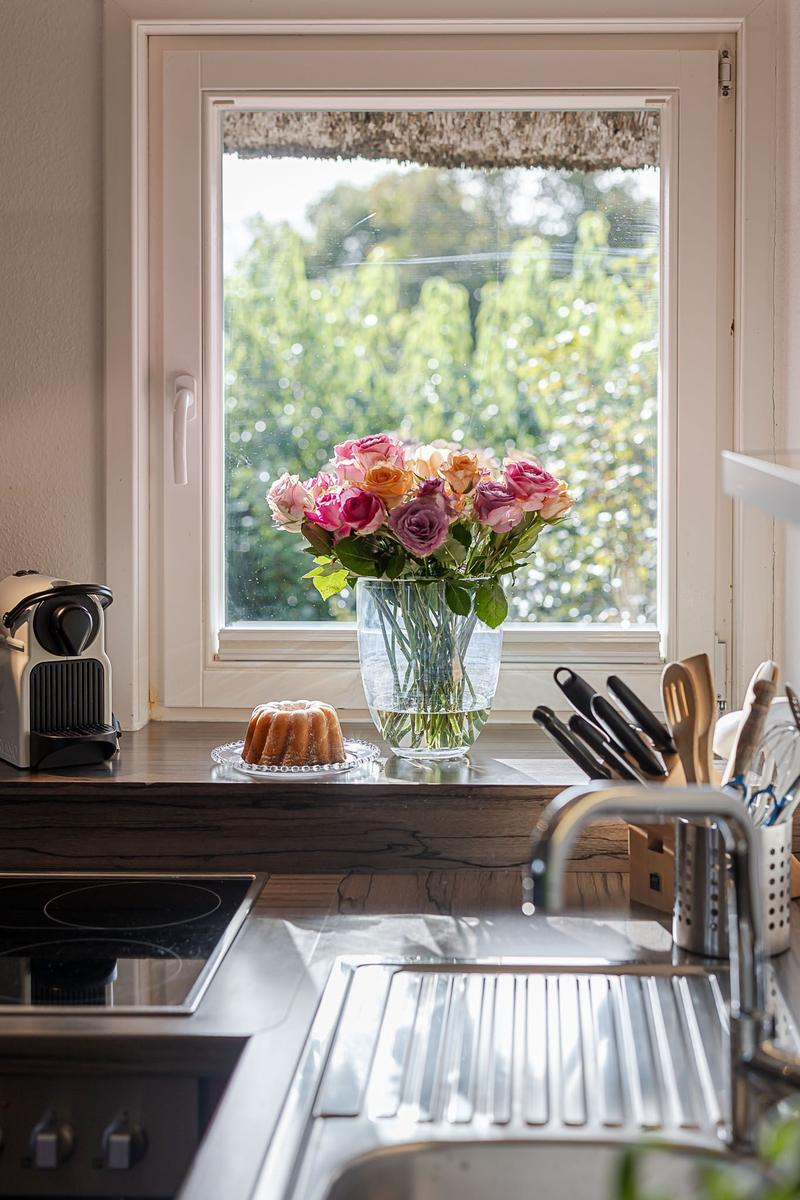 Küchenfenster mit Blumen und Kuchen auf der Arbeitsplatte.