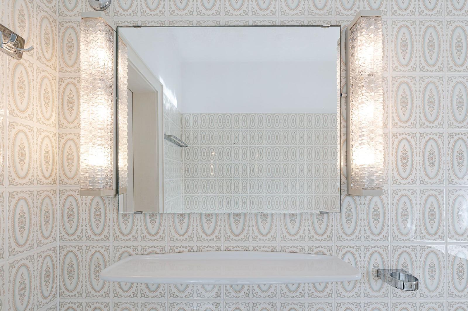 Badezimmer mit Spiegel, zwei Lampen und einer Badewanne