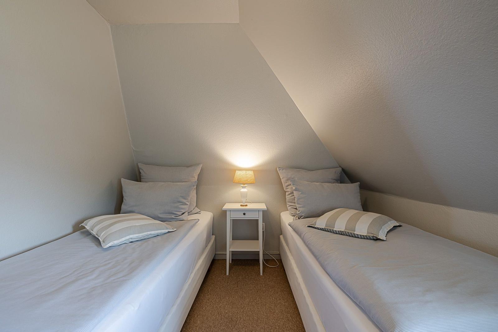 Zwei Betten mit Kissen und einer Lampe zwischen ihnen unter einem Dach