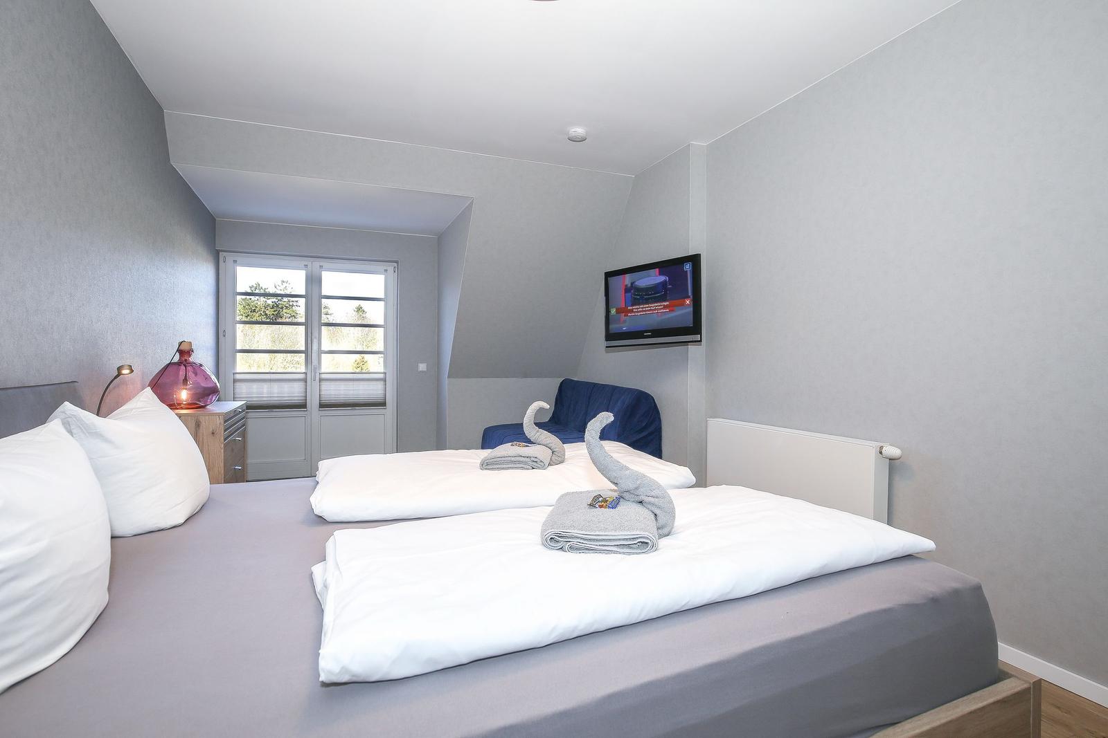 Schlafzimmer mit Doppelbett, TV und Fenster zur Aussicht.