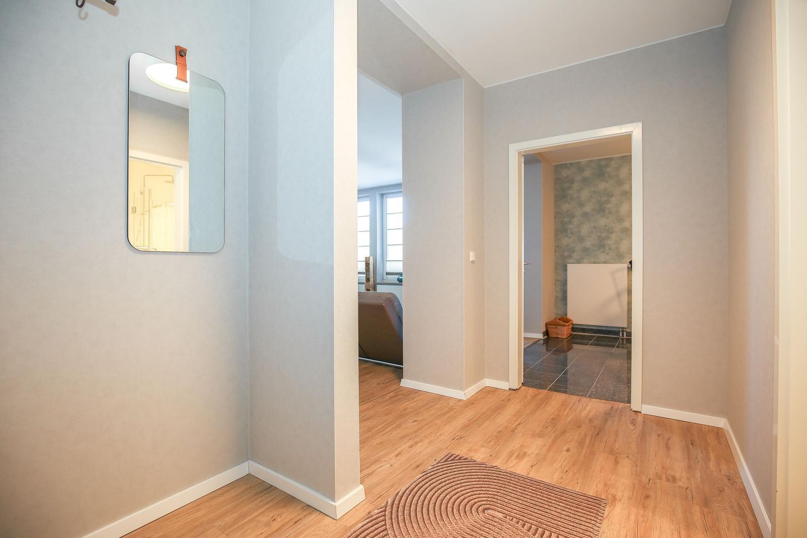 Flur mit Holzboden, Spiegel und Blick in Schlaf- und Badezimmer
