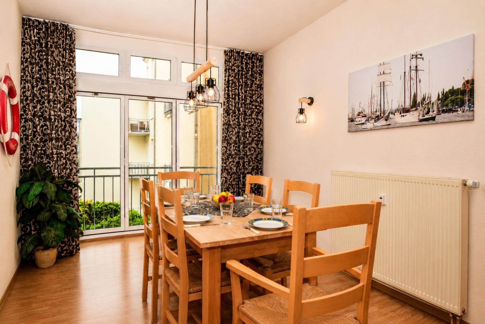 Esszimmer mit Holztisch, Stühlen und Blick auf Balkon.