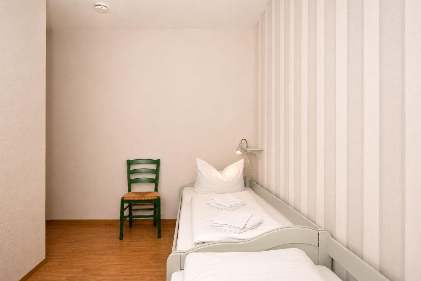 Ein Schlafzimmer mit einem Bett, einer grünen Stuhl und einer Wand mit Streifen.