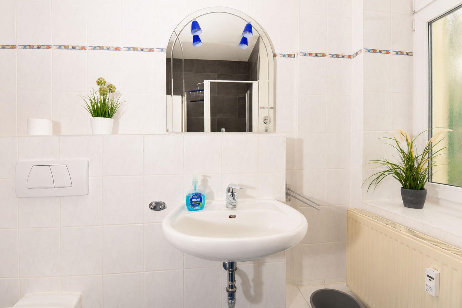 Bad mit Waschbecken, Spiegel und Pflanzen an den Wänden.