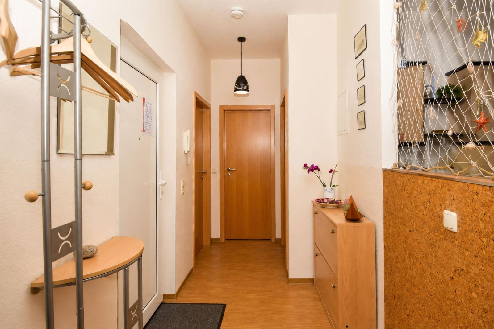 Flur mit Garderobe, Schrank und Holztüren. Wanddekoration und Beleuchtung sichtbar.