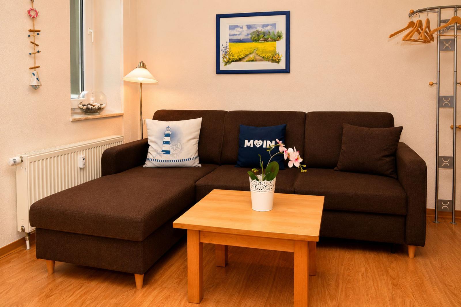 Ein Wohnzimmer mit braunem Sofa, Holztisch und Wandbild.