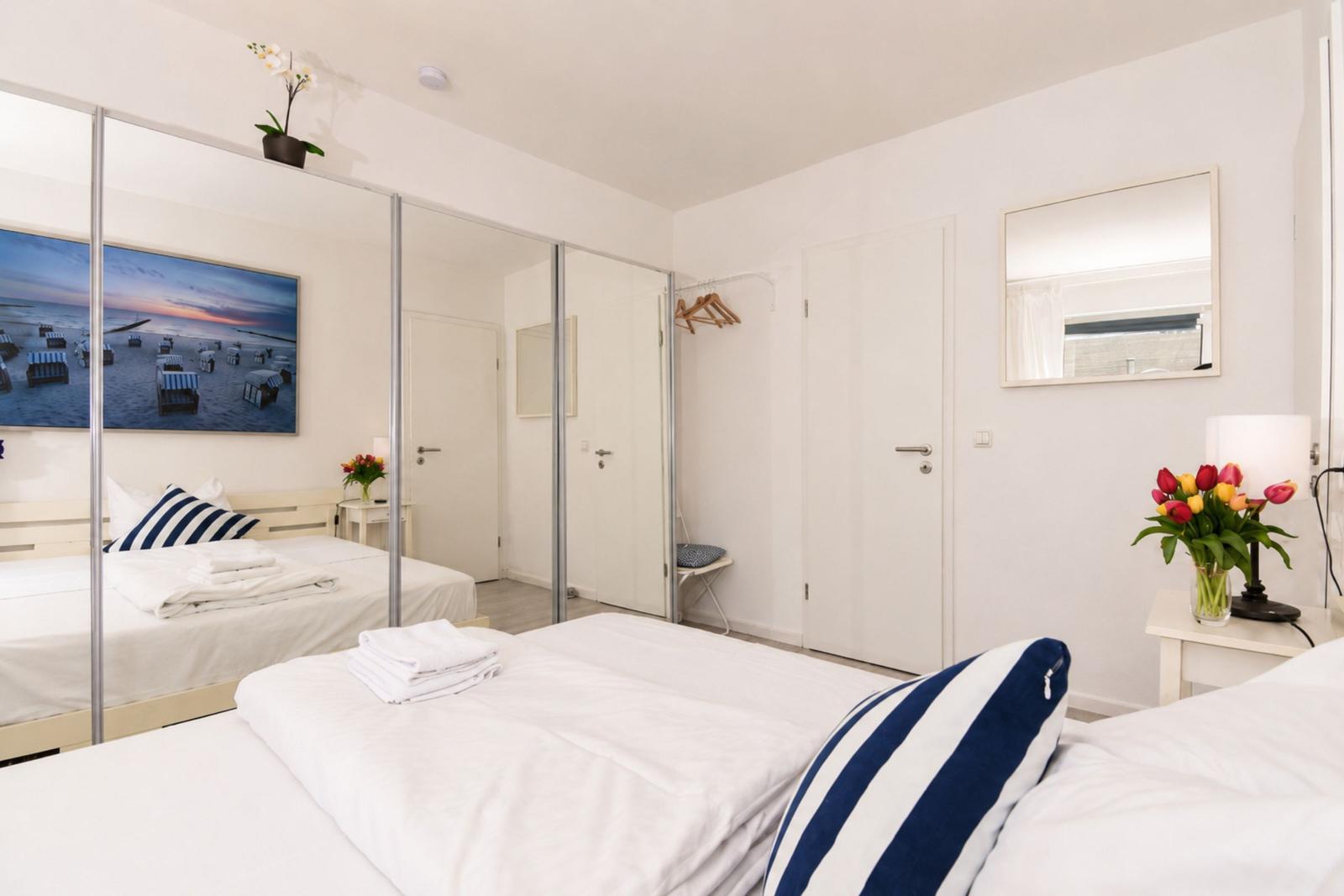 Schlafzimmer mit Doppelbett, Spiegelschrank und Blumenarrangement