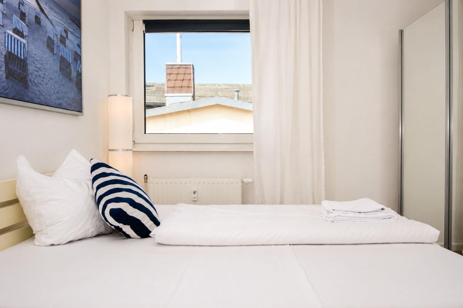 Schlafzimmer mit Bett, Fenster und Wandbild.