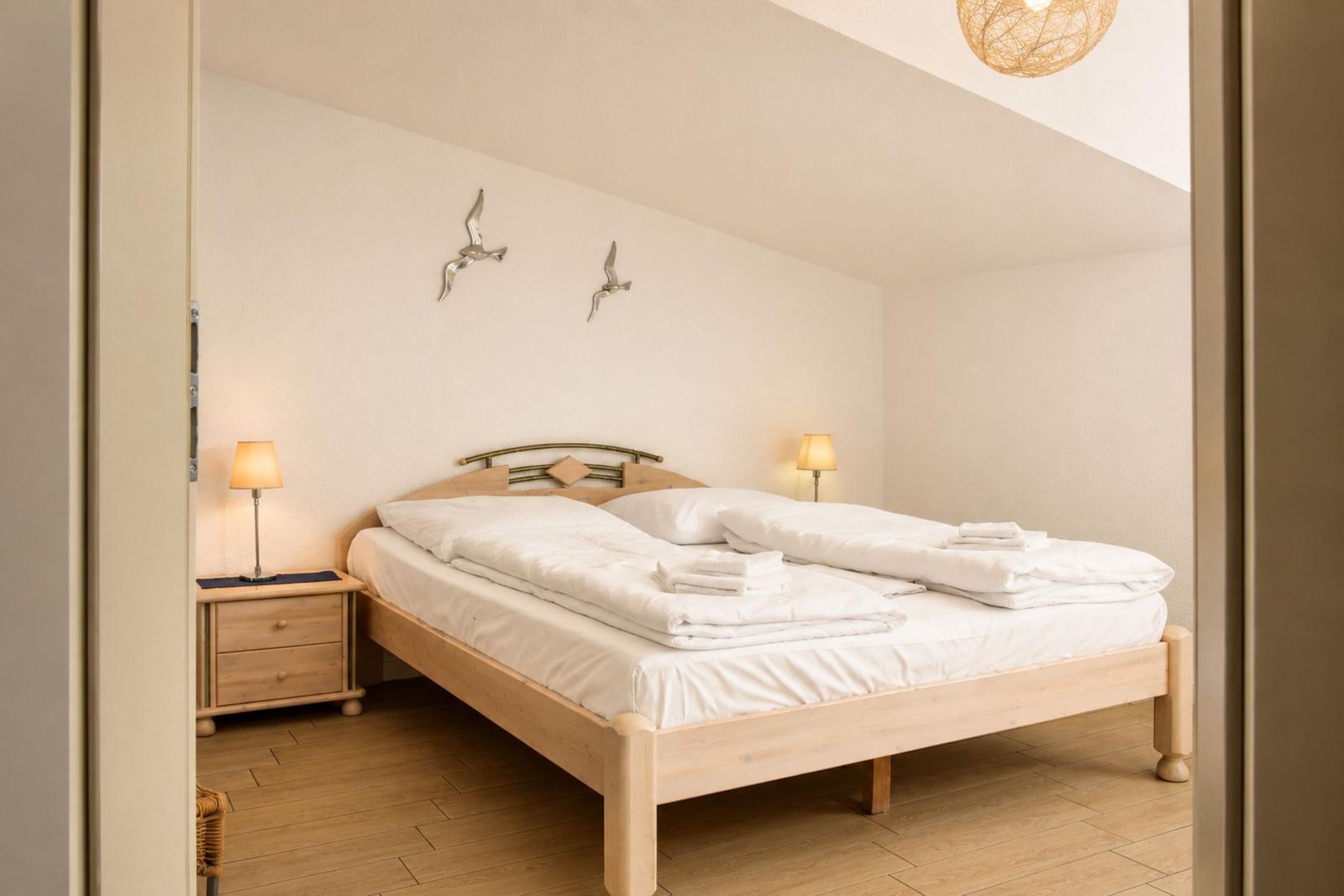 Schlafzimmer mit Doppelbett, Nachttischen und Wanddekoration.