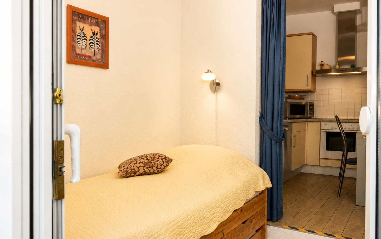 Schlafzimmer mit Bett und Küchenbereich im Hintergrund