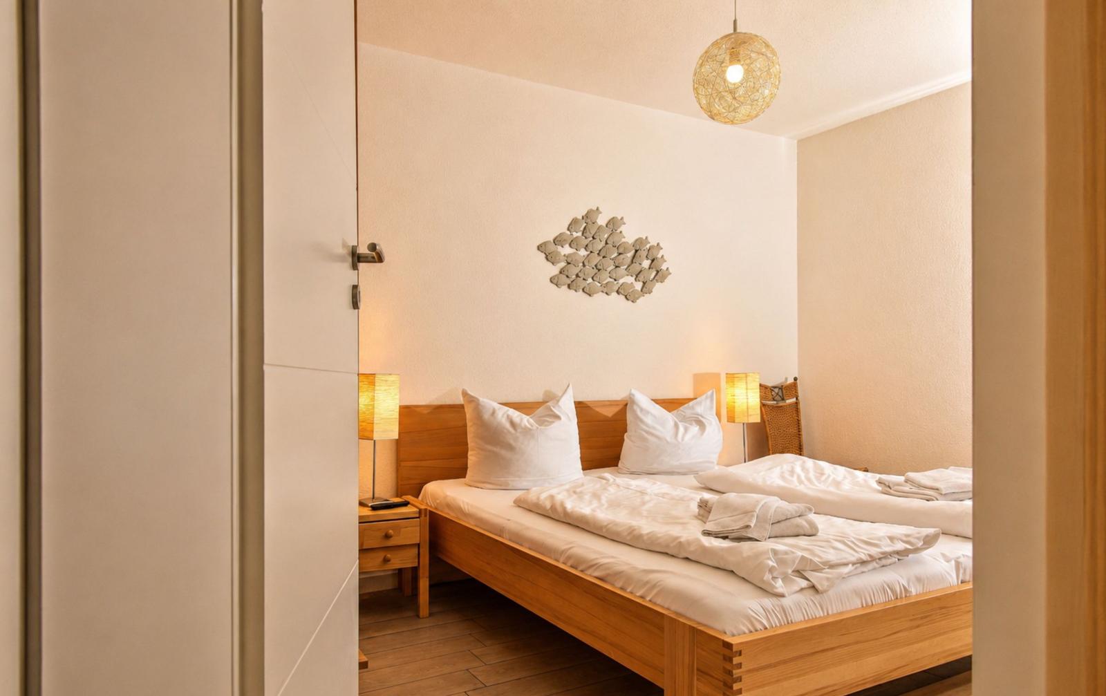 Schlafzimmer mit Holzbett, Nachttisch und Deckenbeleuchtung.