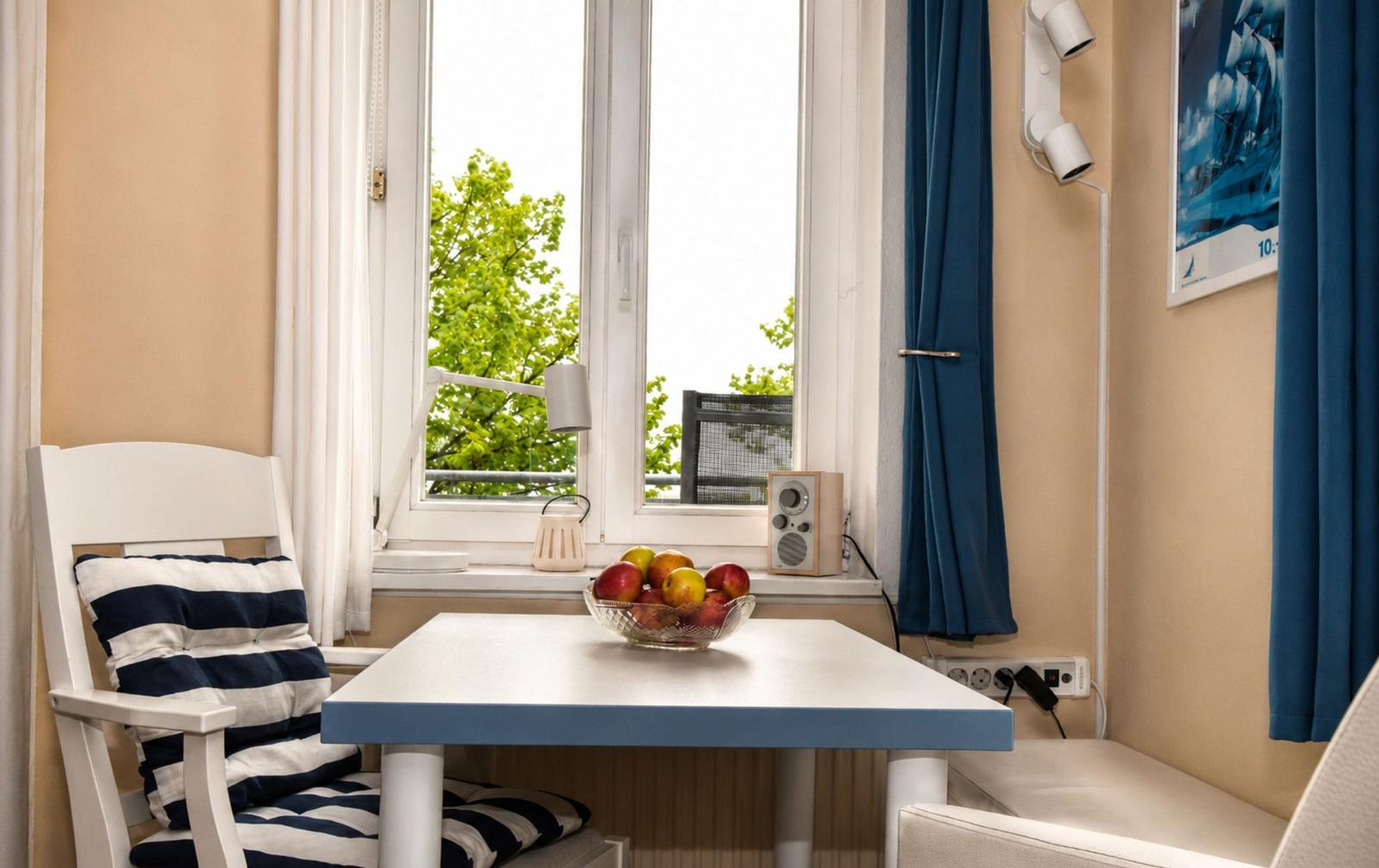 Ein Tisch mit Obst steht vor einem Fenster mit Blick auf Bäume.