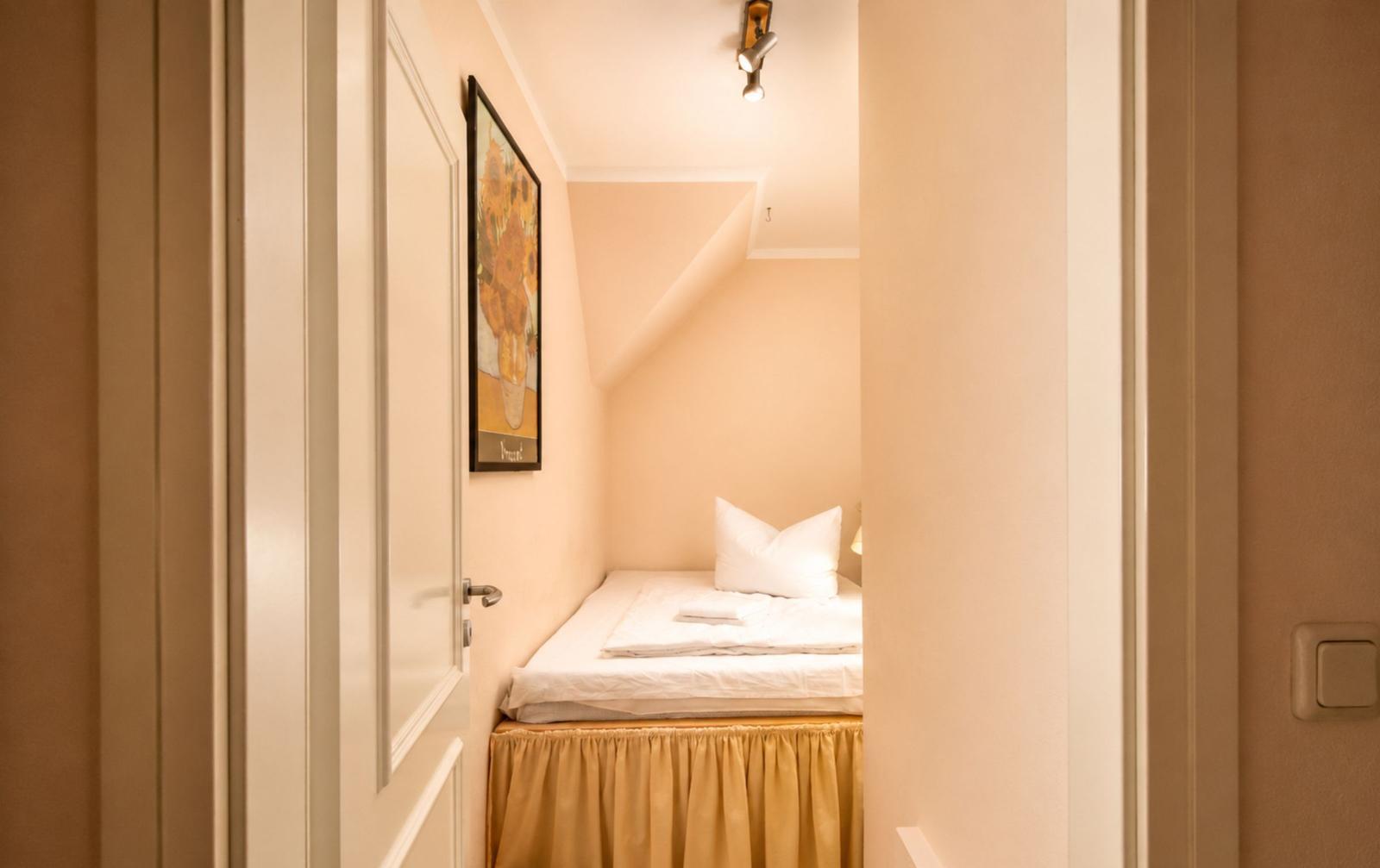 Ein Schlafzimmer mit Dachschrägen, Bett mit weißer Bettwäsche und einem Bild an der Wand.