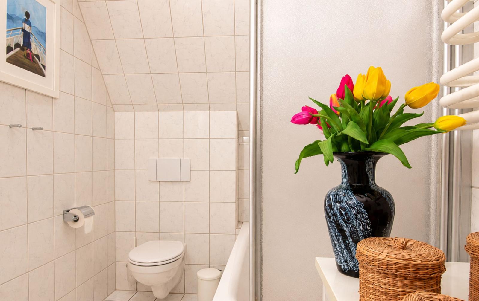 Badezimmer mit Toilette, Blumen in Vase und Heizung
