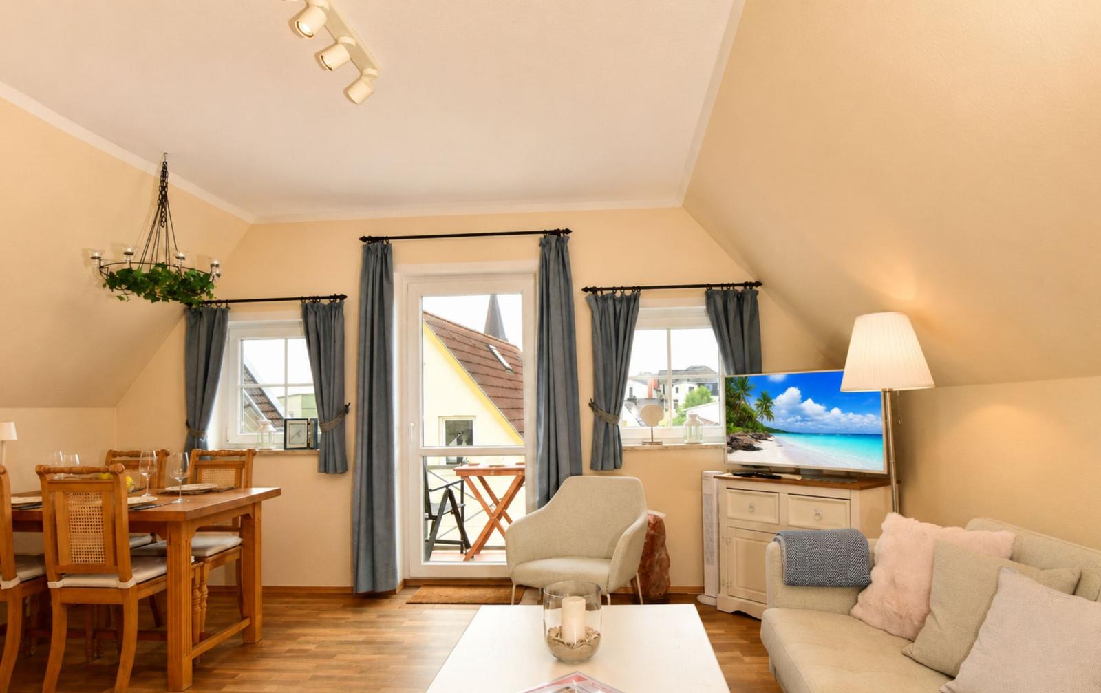 Wohn- und Essbereich mit TV, Balkon und Holzmöbeln.